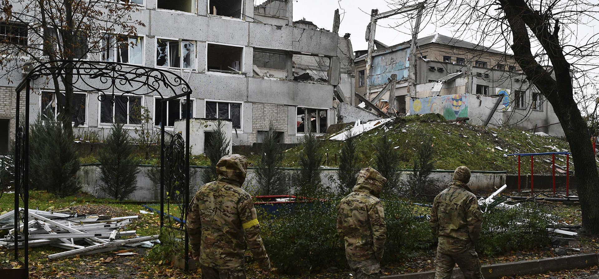 Militares ucranianos pasan junto a edificios dañados por bombardeos rusos en Druzhkivka, región de Donetsk, Ucrania, el miércoles 26 de octubre de 2022.
