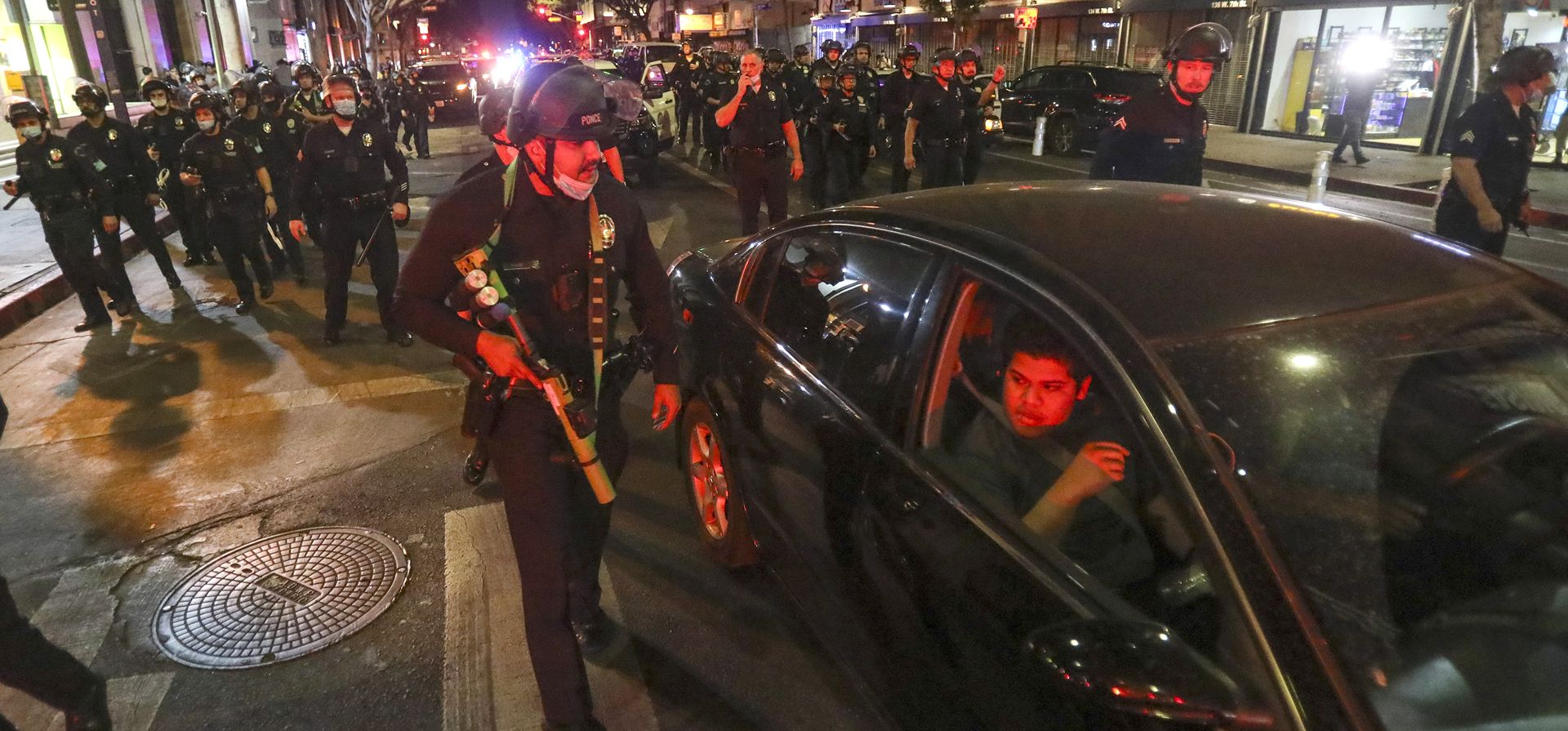 La policía antidisturbios despeja las calles mientras los fanáticos del fútbol celebran después de que los Rams de Los Ángeles derrotaran a los Bengals de Cincinnati durante el partido de fútbol americano Super Bowl 56 de la NFL, el domingo 13 de febrero de 2022, en el centro de Los Ángeles, California.