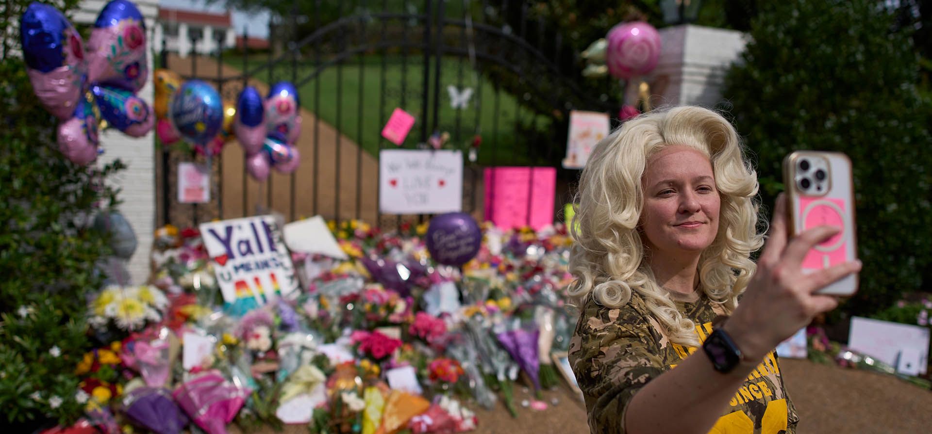 Mandy Madson, luciendo una peluca inspirada en Dolly Parton, se toma una selfie en un improvisado monumento conmemorativo frente a la casa de la fallecida Dolly Parton en Brentwood, Tennessee, el miércoles 26 de agosto de 2026. (Foto AP/George Walker IV)
