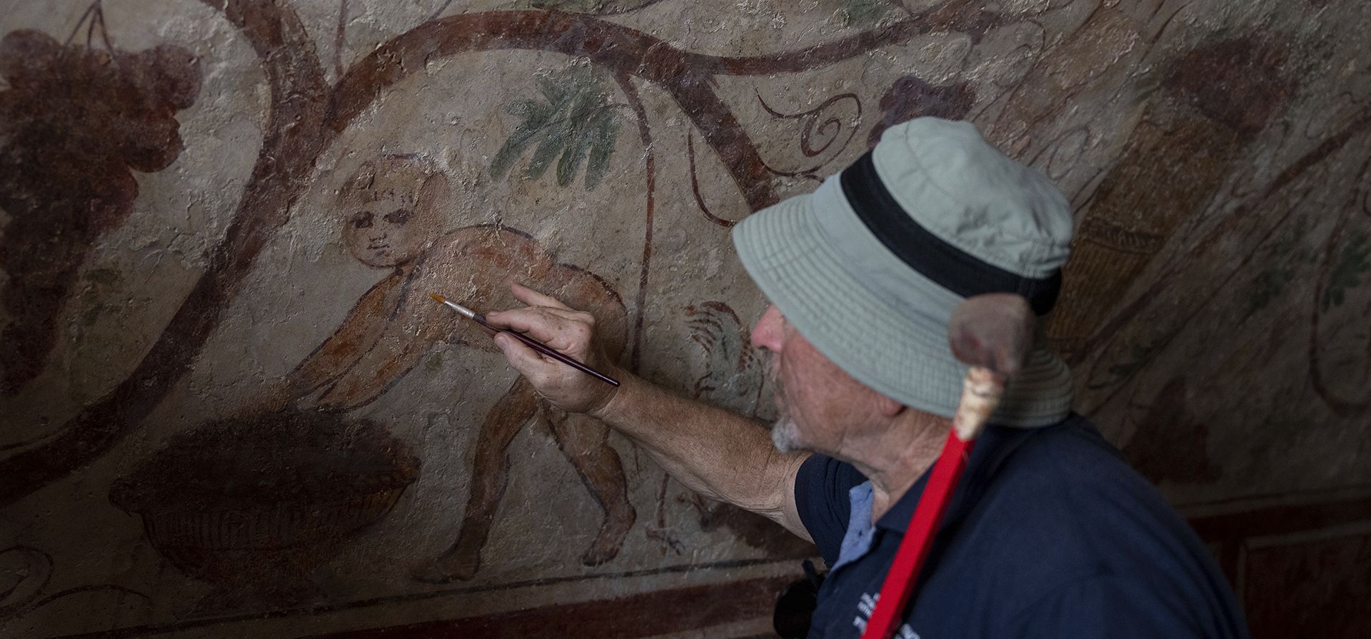 Un trabajador señala una pared antigua del sitio arqueológico de Ashkelon, Israel, el martes 27 de agosto de 2024. La tumba con pinturas murales que representan figuras mitológicas griegas tiene al menos 1.700 años de antigüedad, según informó la Autoridad de Antigüedades de Israel, cuyos trabajadores están restaurando el sitio. (Foto AP/Ohad Zwigenberg) Un trabajador señala una pared antigua del sitio arqueológico de Ashkelon, Israel, el martes 27 de agosto de 2024. La tumba con pinturas murales que representan figuras mitológicas griegas tiene al menos 1.700 años de antigüedad, según informó la Autoridad de Antigüedades de Israel, cuyos trabajadores están restaurando el sitio. (Foto AP/Ohad Zwigenberg)