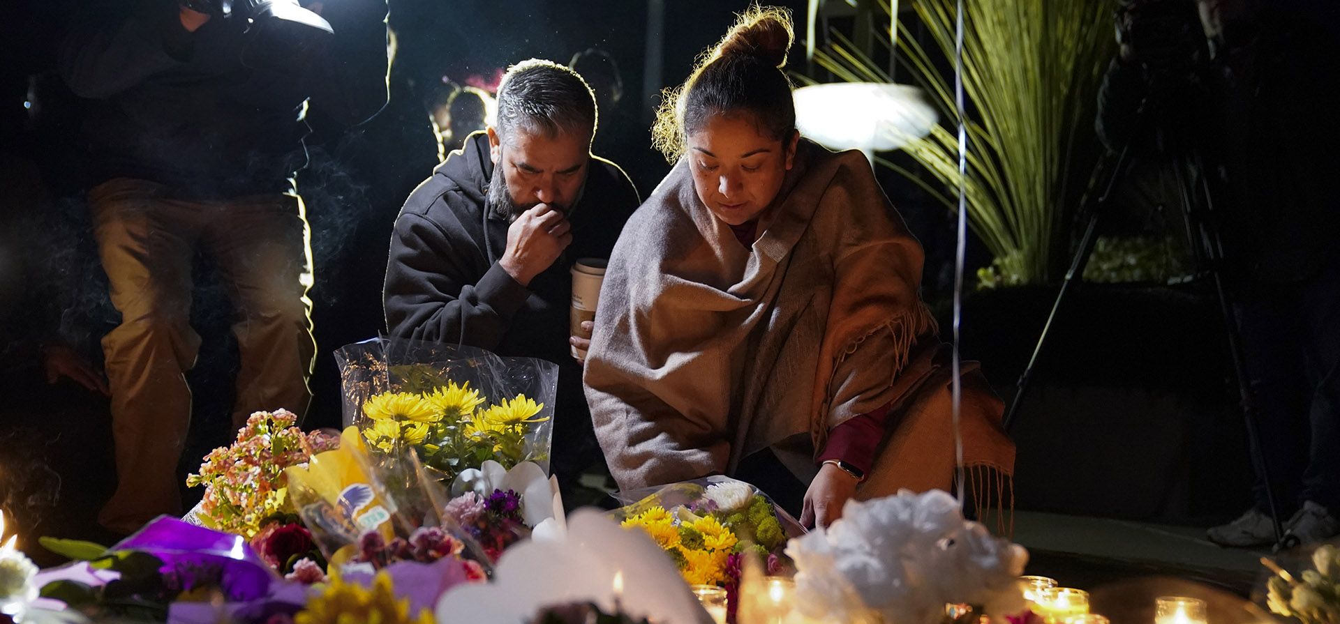 Una pareja hace una pausa en un monumento en una vigilia en honor a las víctimas de un tiroteo en Star Ballroom Dance Studio, el lunes 23 de enero de 2023 en la noche en Monterey Park, California. Un hombre armado mató a varias personas el sábado en la noche en medio de las celebraciones del Año Nuevo Lunar en el comunidad predominantemente asiático-estadounidense. (Foto AP/Ashley Landis)