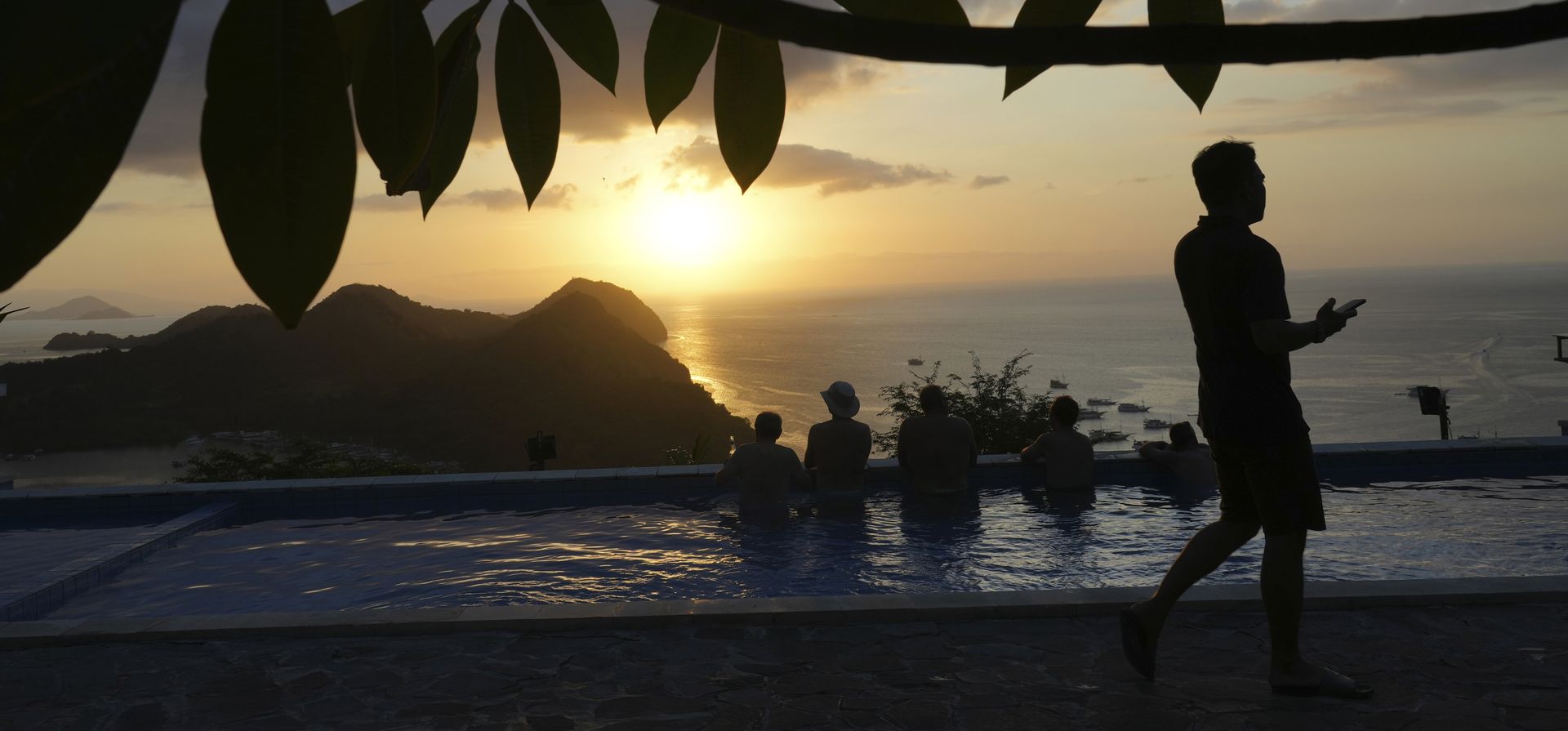 Turistas contemplan una puesta de sol desde una piscina en Labuan Bajo, provincia de Nusa Tenggara Oriental, Indonesia, el jueves 11 de mayo de 2023. (Foto AP/Achmad Ibrahim)