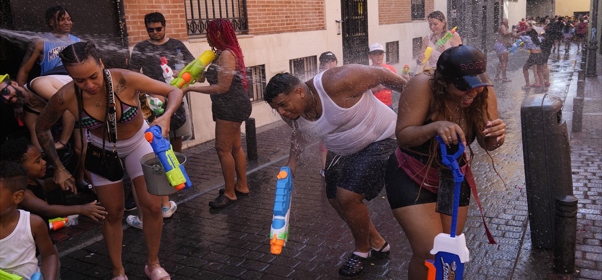 Personas disparan pistolas de agua durante una pelea de agua en un día caluroso en el distrito de Vallecas de Madrid, España. (Foto AP/Paul White)