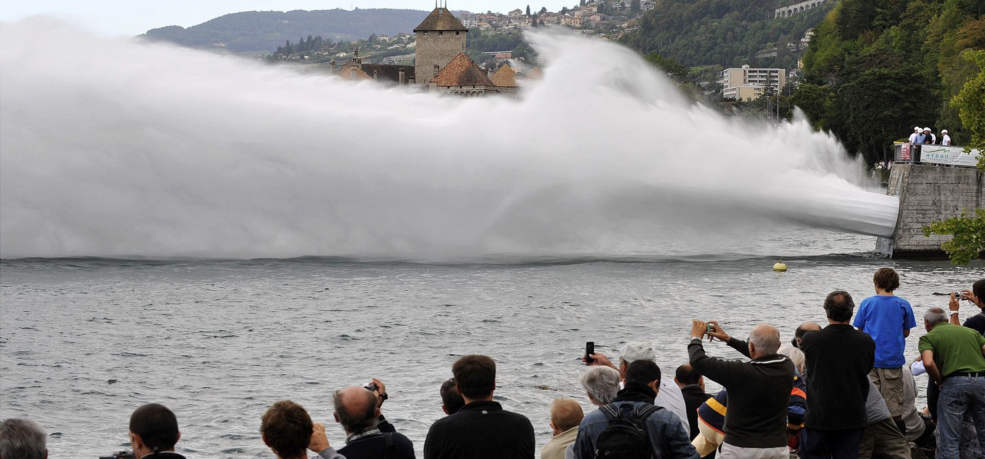 La gente observa un enorme chorro de agua de 350 m de longitud que lanza 20.000 litros de agua por segundo al lago Ginebra, durante una revisión funcional de la central hidroeléctrica Forces Motrices Hongrin-Leman en Veytaux, Suiza.