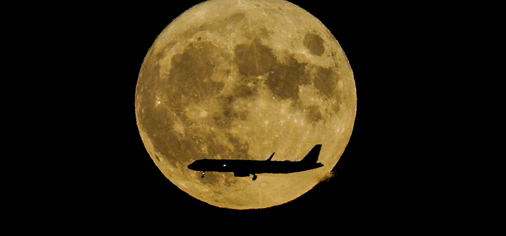 Una superluna, también llamada luna del esturión, se eleva cuando un avión de pasajeros se acerca al aeropuerto internacional John F. Kennedy, madrugada 12 de agosto de 2022, en Nueva York. (Foto AP/Bebeto Matthews)