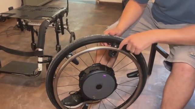 Luciano muestra las ruedas especiales de la silla que donaron para Matías Bottoni