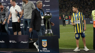 Miguel Angel Russo recibió su medalla y camina detrás de la copa que conquistó Central. El nieto del DT, también con una medalla, lo espera.