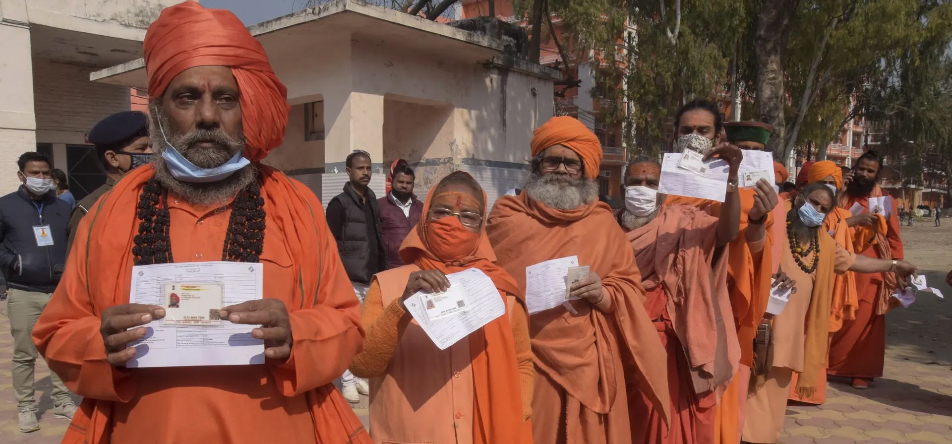 Hombres y mujeres santos hindúes se alinean para emitir sus votos durante las elecciones a la asamblea estatal de Uttarakhand, Haridwar, India. 