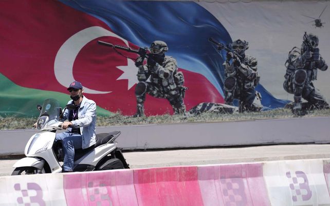 Un hombre conduce una scooter junto a un cartel antes del Gran Premio de Fórmula Uno en el circuito urbano de Fórmula Uno de Bakú en Bakú