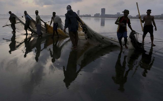 Pescadores paquistaníes arrastran sus redes mientras se van después de pescar peces en el mar en la playa de Karachi