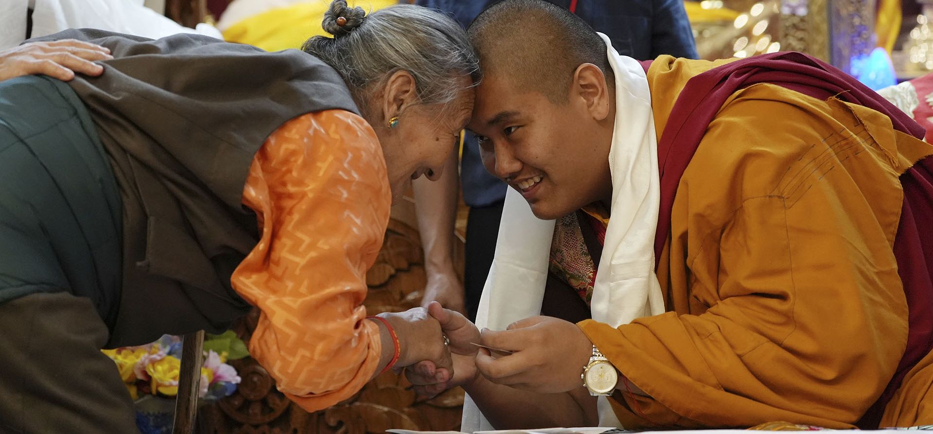 El lama budista nacido en Estados Unidos, Jalue Dorje, a la derecha, y un miembro de la comunidad tibetana de Minnesota se inclinan y se tocan la frente en un saludo tibetano tradicional durante su 18º cumpleaños y ceremonia de entronización en Isanti, Minnesota, el sábado 9 de noviembre de 2024. (Foto AP/Luis Andres Henao)