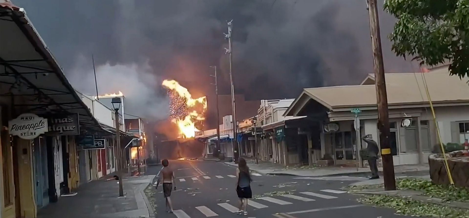 Varias personas observan mientras el humo y las llamas de los incendios forestales llegan a Front Street, en el centro de Lahaina, en Maui, Hawai, el 8 de agosto de 2023. (Alan Dickar vía AP)