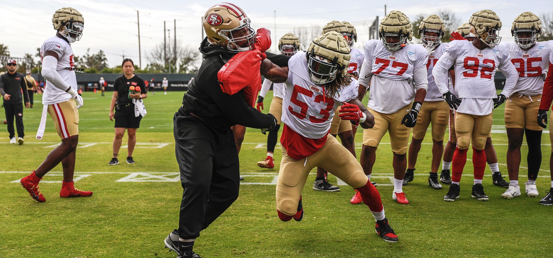 El jugador de los 49ers de San Francisco, Kemoko Turay (53), practica con un entrenador durante ejercicios en el campo de entrenamiento del equipo de fútbol americano de la NFL en Santa Clara, California, el martes 2 de agosto de 2022.