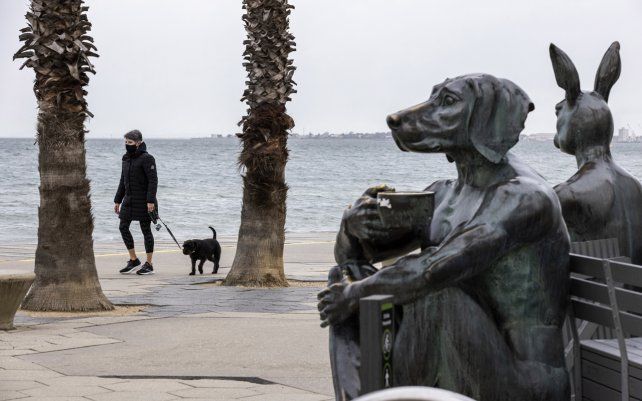 Una persona pasea a un perro a lo largo de la playa de St. Kilda en Melbourne. La ciudad reportó 22 nuevos contagios, la ciudad más grande de Australia después de Sydney estaba en un