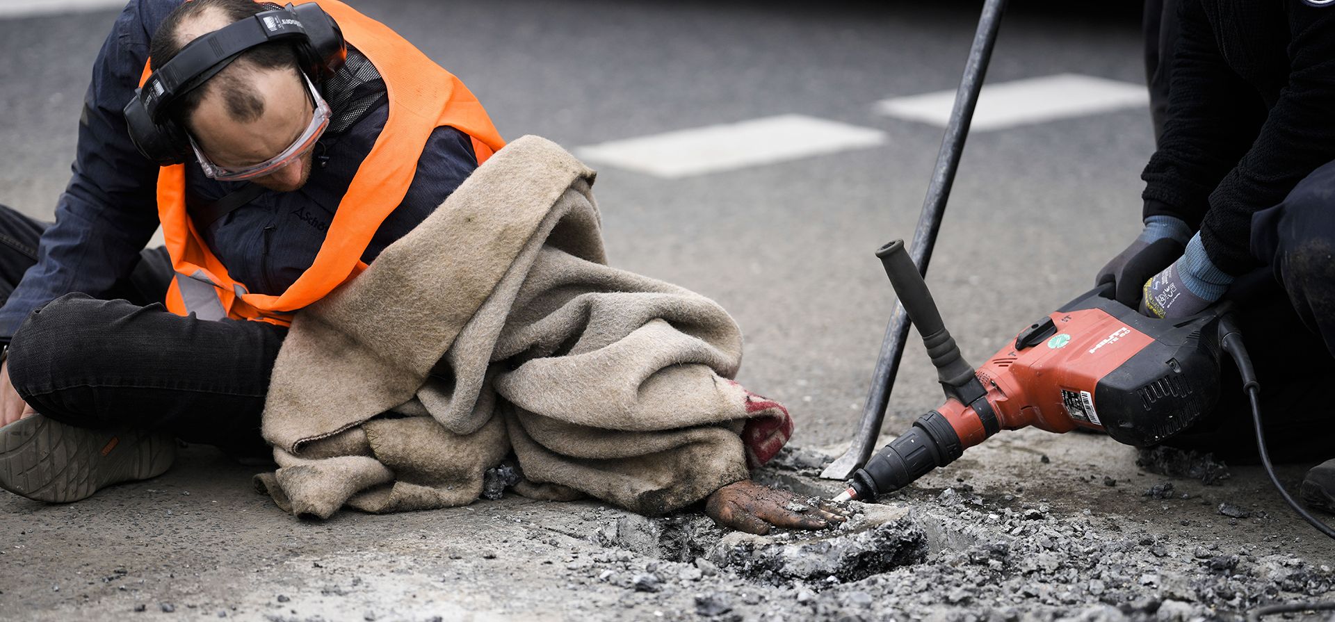 La policía quita el asfalto junto a la mano de un activista climático que pegó su mano en la carretera, durante una protesta contra la política climática del gobierno alemán en Berlín, Alemania.