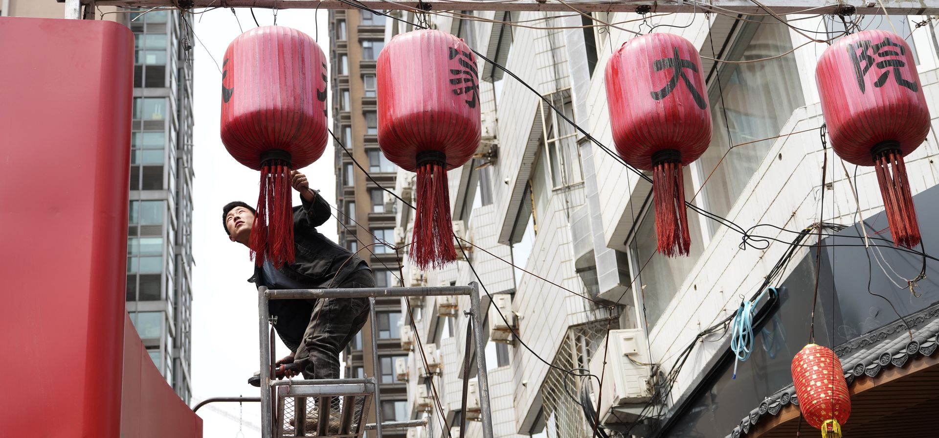 Un trabajador reemplaza las linternas rojas afuera de un restaurante en Beijing, el jueves 11 de mayo de 2023. (Foto AP/Ng Han Guan)