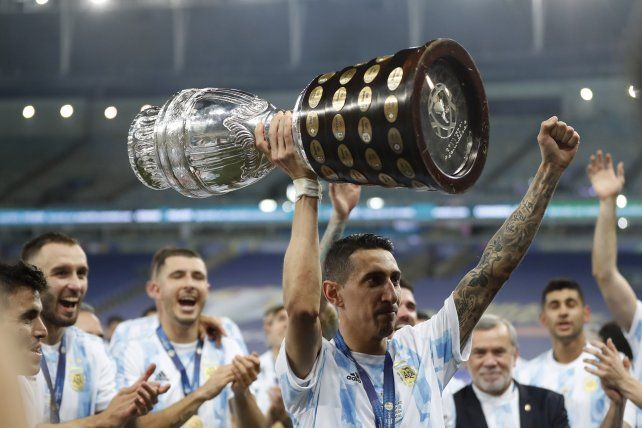 El rosarino Ángel Di María, centro, sostiene el trofeo mientras celebra con sus compañeros de equipo después de vencer 1-0 a Brasil en la final de la Copa América en el estadio Maracaná de Río de Janeiro, Brasil, el sábado 10 de julio de 2021.AP Photo / Andre Penner