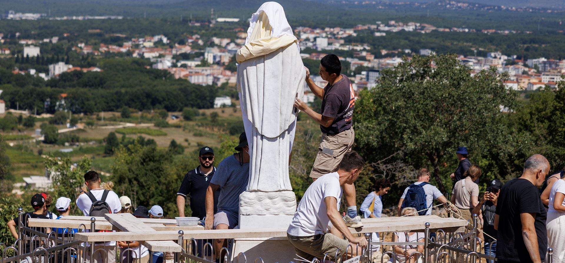Voluntarios limpian la estatua vandalizada de la Virgen María, que ha sido cubierta con una sábana blanca, en la Colina de las Apariciones en Medjugorje, Bosnia, el 28 de julio de 2026. (Foto AP)