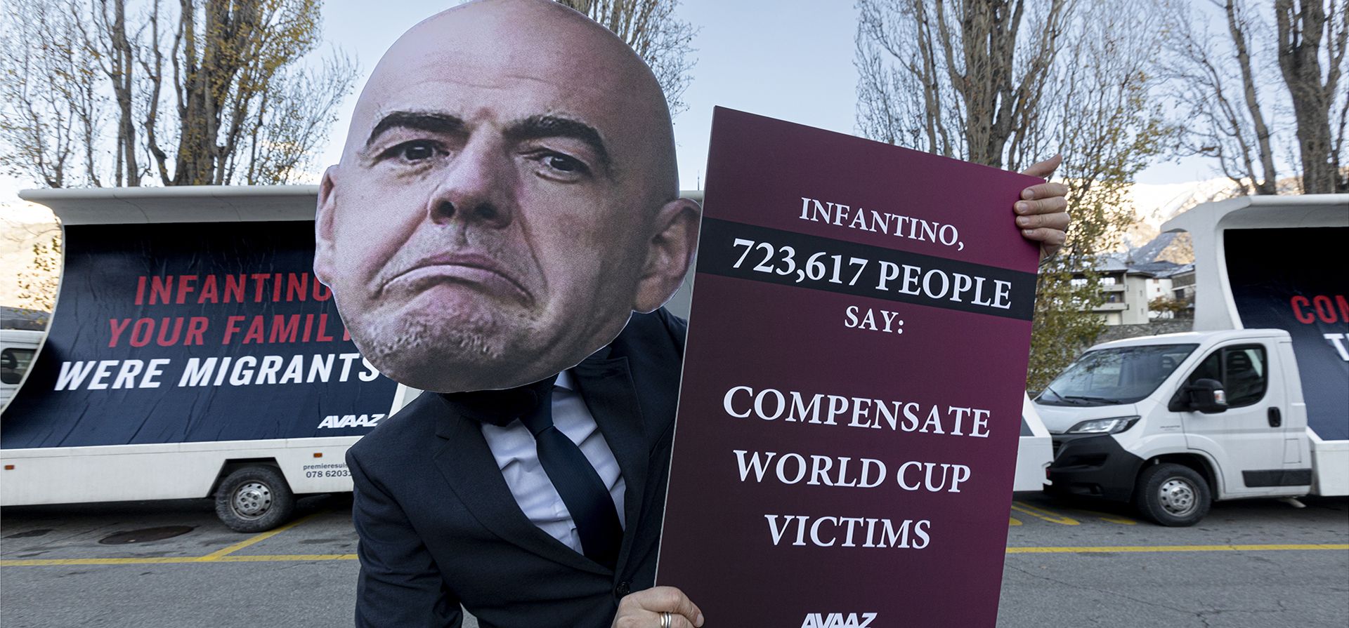 Una persona que simula ser Gianni Infantino se colca delante de vallas publicitarias que exigen compensación para los trabajadores migrantes víctimas de la Copa del Mundo en Qatar, en la ciudad natal del presidente de la FIFA, el jueves 8 de diciembre de 2022, en Brig, Suiza. (Alberto Bernasconi/AP Imágenes para Avaaz)