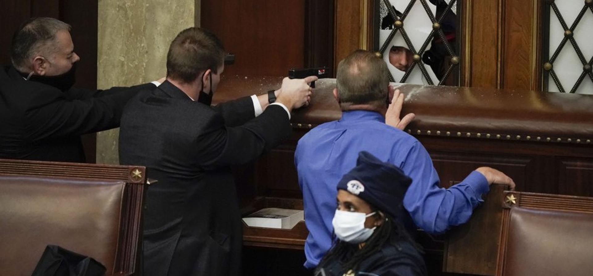 Agentes de seguridad apuntan con sus armas a los seguidores de Donald Trump que irrumpieron de forma violenta en el Capitolio el 6 de enero. Foto: AP