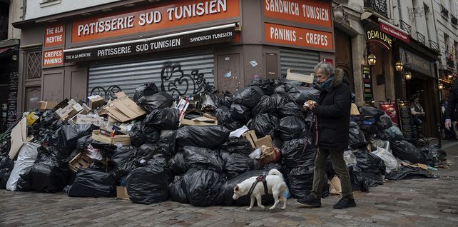 Un hombre pasa junto a montones de basura en París