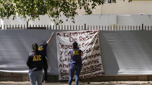 Personal de la Agencia de Investigación Criminal retira el trapo que los delincuentes colgaron este martes frente a Telefe Rosario.&nbsp;