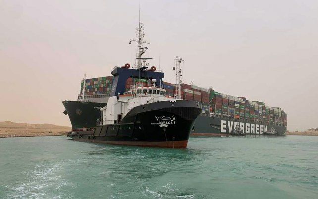 Un remolcador pasa junto al buque portacontenedores llamado Ever Given, operado por Evergreen Marine, después de que encalló en el extremo sur del Canal de Suez, bloqueando el tráfico de navegación en ambas direcciones. El barco giró de costado en el Canal mientras se dirigía de China a Rotterdam.