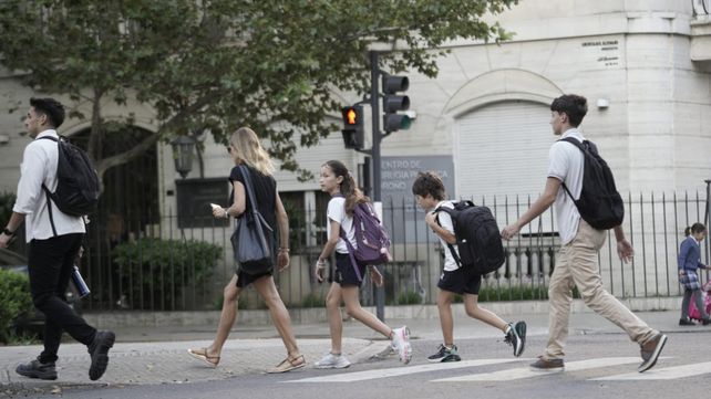 Los chicos cargan sus mochilas camino al primer d&iacute;a de clases.