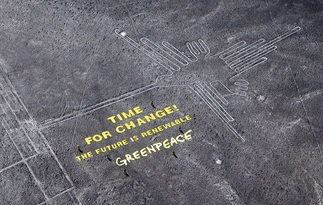 Activistas de Greenpeace junto al mensaje instalado a metros del Colibrí de Nasca.