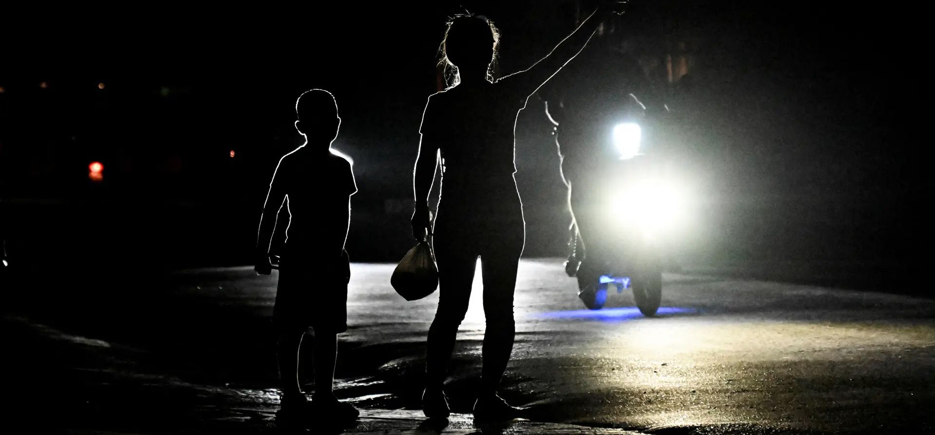 Una mujer con su hijo le hace señas a un automóvil en una calle oscura durante un apagón en el municipio de Bauta, provincia de Artemisa. Fotografía: Yamil Lage/AFP/Getty Images Una mujer con su hijo le hace señas a un automóvil en una calle oscura durante un apagón en el municipio de Bauta, provincia de Artemisa. Fotografía: Yamil Lage/AFP/Getty Images