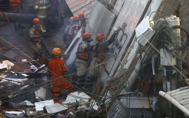 Los bomberos usan un perro rastreador para buscar posibles sobrevivientes en un edificio de cuatro pisos que se derrumbó durante la noche en el barrio humilde de Rio das Pedras en Río de Janeiro