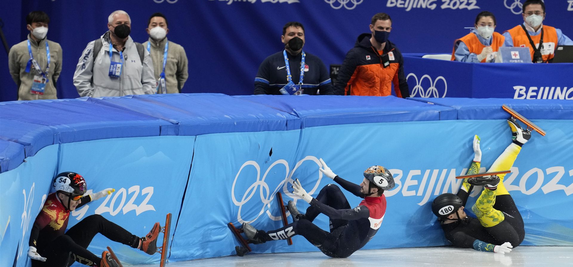 Ren Ziwei, de China, a la izquierda, Brendan Corey de Australia, e Itzhak Laat, de Holanda, en el centro, chocan en los cuartos de final de los 1.000 metros masculinos durante la competencia de patinaje de velocidad en pista corta de los Juegos Olímpicos de Invierno de 2022.