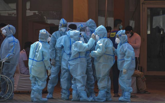 Trabajadores de la salud y voluntarios esperan recibir a los pacientes fuera de un hospital que se instaló en un Sikh Gurdwara