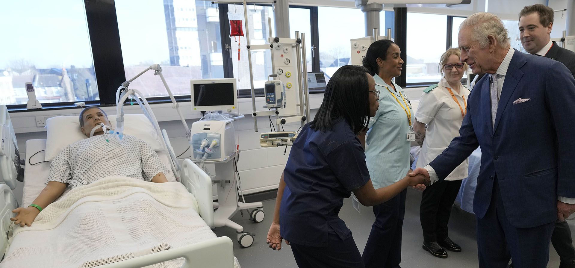 El rey Carlos III de Gran Bretaña habla con estudiantes y pasantes en la sala de cuidados intensivos durante su visita a la Universidad de East London para conmemorar el 125º aniversario de la universidad y abrir un nuevo centro de enseñanza médica de primera línea en Londres, el miércoles 8 de febrero de 2023. (Foto AP /Frank Augstein, Piscina)