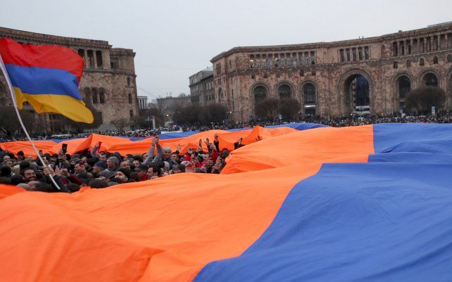 Una multitud sostiene una enorme bandera nacional armenia durante un mitin de partidarios del primer ministro Nikol Pashinyan en el centro de Ereván, Armenia. La oposición está organizando manifestaciones rivales masivas en la capital de Ereván.