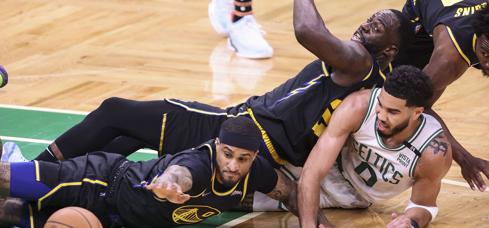 Draymond Green, Andrew Wiggins y Gary Payton II de Golden State Warriors luchan por el balón contra Jayson Tatum de Boston Celtics, abajo a la derecha, durante el primer cuarto del Juego 3 de las Finales de baloncesto de la NBA.
