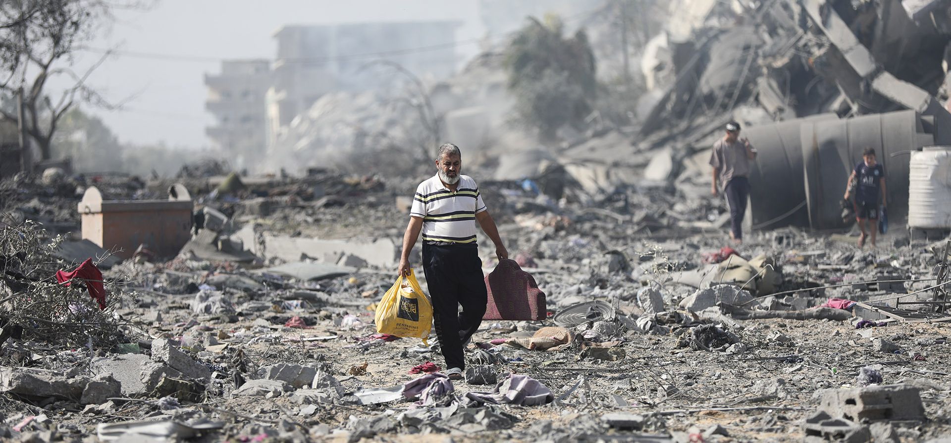 Palestinos caminan junto a los edificios destruidos por el bombardeo israelí en al-Zahra, en las afueras de la ciudad de Gaza, el viernes 20 de octubre de 2023. (Foto AP/Ali Mahmoud) Palestinos caminan junto a los edificios destruidos por el bombardeo israelí en al-Zahra, en las afueras de la ciudad de Gaza, el viernes 20 de octubre de 2023. (Foto AP/Ali Mahmoud)