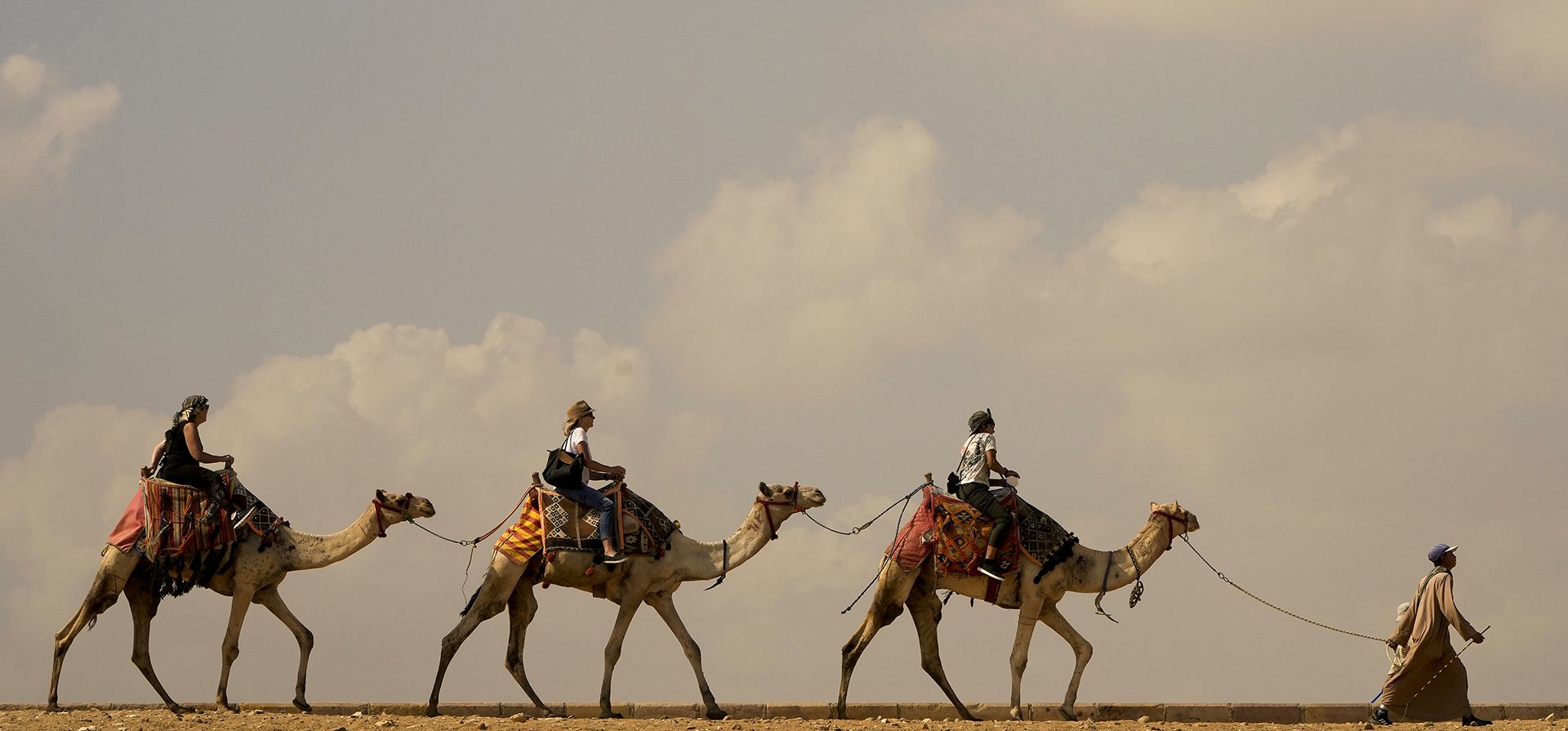 Turistas dan un paseo en camello en los alrededores de las pirámides de Giza en Giza, cerca de El Cairo, Egipto, el miércoles 2 de noviembre de 2022.