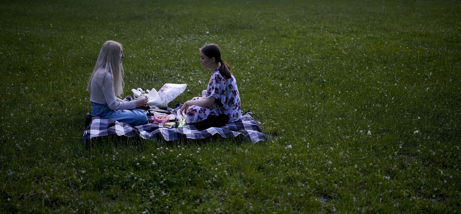 Dos mujeres jóvenes se sientan para disfrutar de un picnic en el parque Natalka en Kyiv.