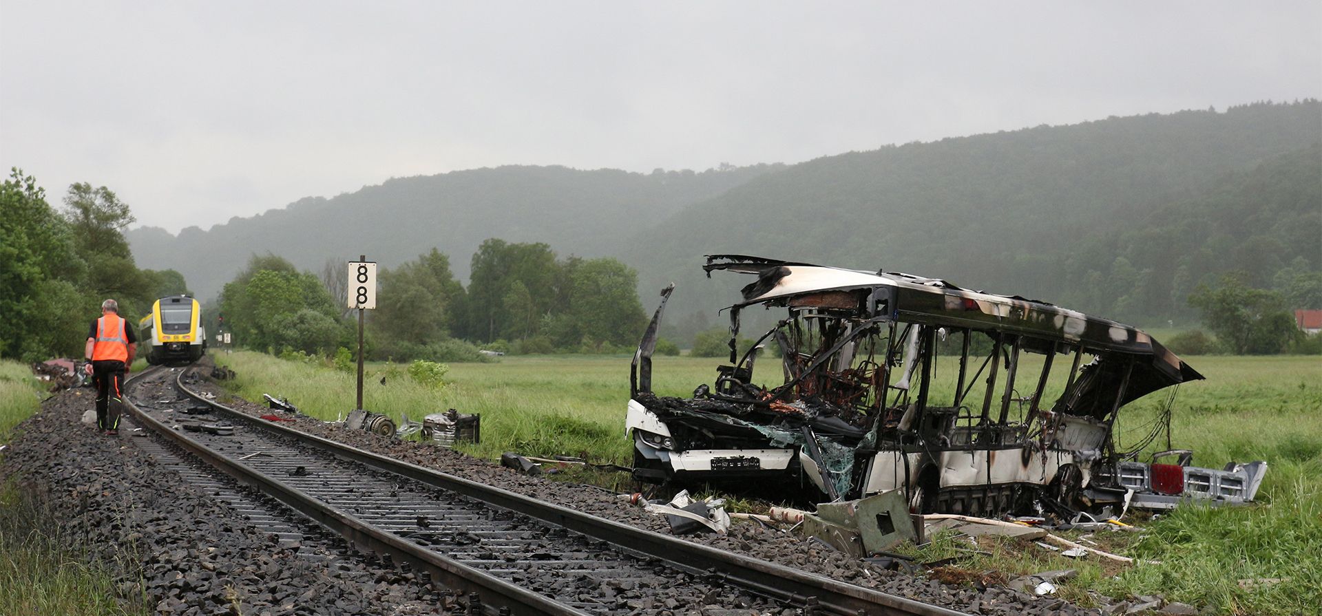 Los restos de un autobús al costado de las vías del tren son retirados después de una colisión con un tren en Blaustein, cerca de Ulm, Alemania, el martes 24 de mayo de 2022. Varias personas resultaron heridas cuando un autobús chocó con un tren en un cruce ferroviario en el sur de Alemania.