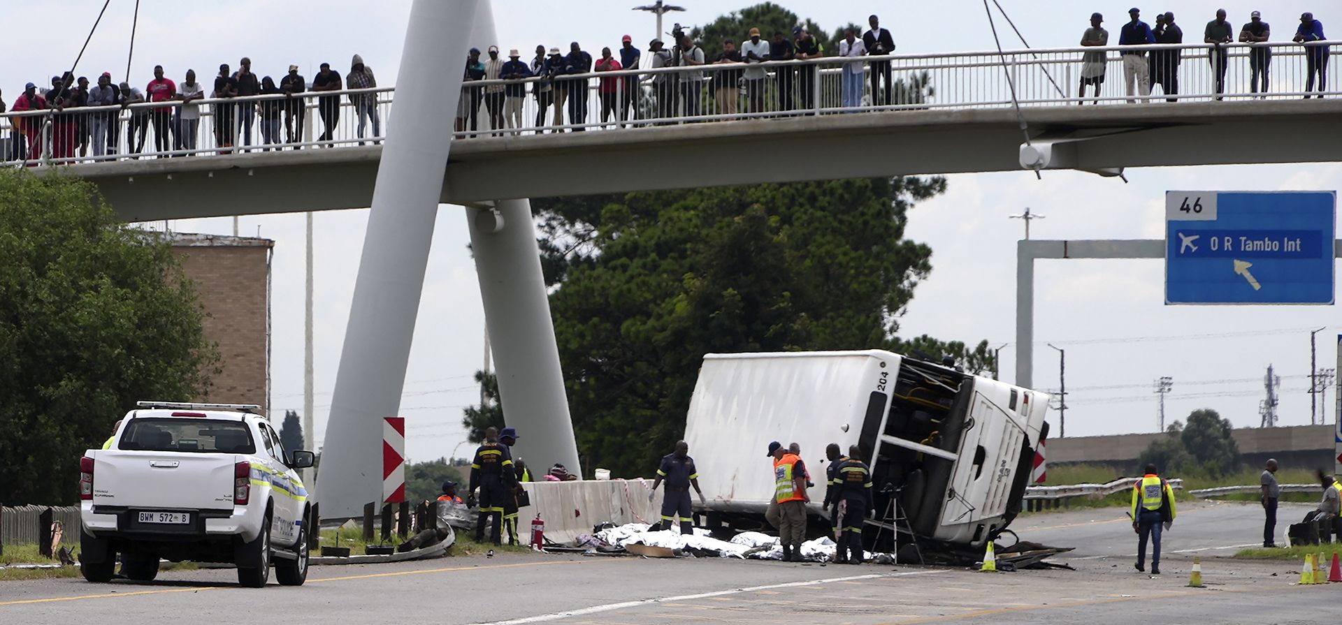La gente observa desde un puente a los agentes de emergencia que investigan un autobús que volcó en una autopista en Johannesburgo, Sudáfrica, el martes 11 de marzo de 2025, matando a varias personas y dejando a otras heridas. (Foto AP/Alfonso Nqunjana)