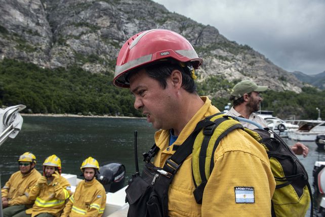 Bomberos se desplazan en lanchas por el lago hacia la zona del fuego.