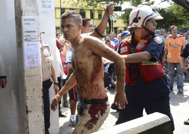 Un rescatista camina con un hombre no identificado herido durante el motín. (Foto: Reuters)