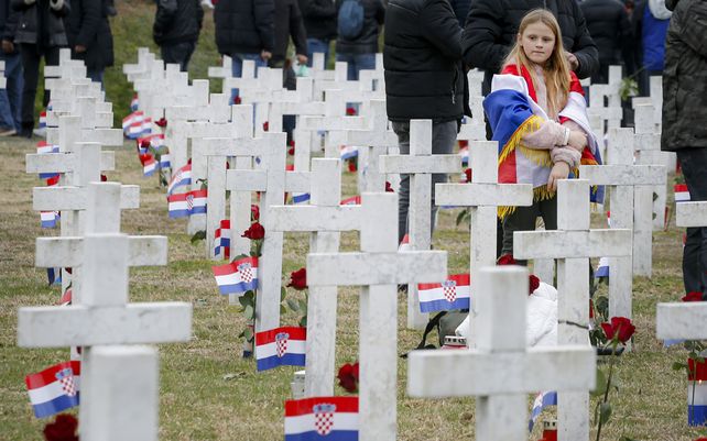 Una niña envuelta en la bandera croata observa el cementerio conmemorativo de Vukovar