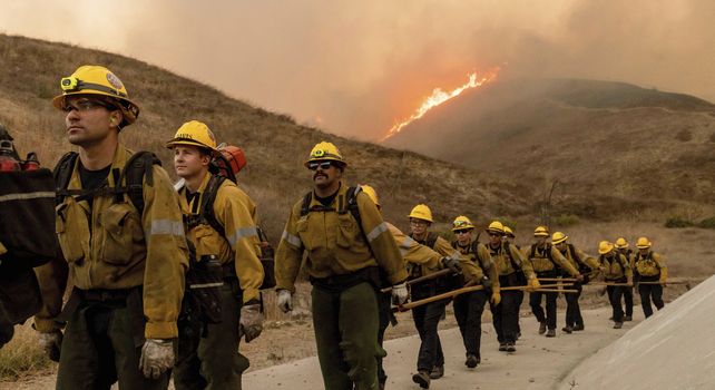Los equipos de bomberos caminan mientras luchan contra el incendio Kenneth en la sección West Hills de Los Ángeles.