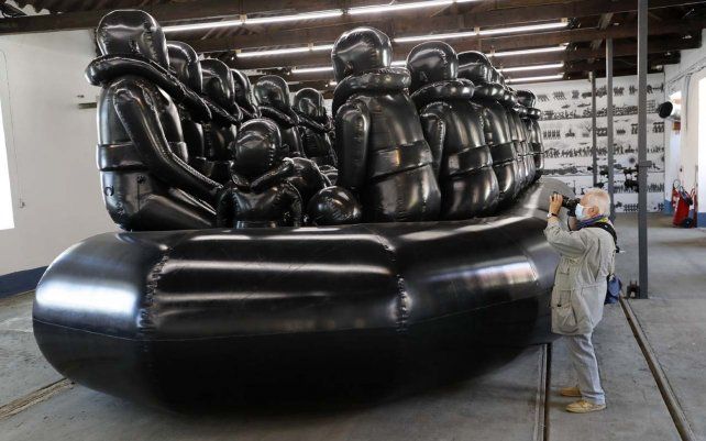 Un fotógrafo retrata una obra de arte del artista chino disidente Ai Weiwei, un bote inflable gigante para migrantes, durante una vista previa para la prensa de su nueva exposición