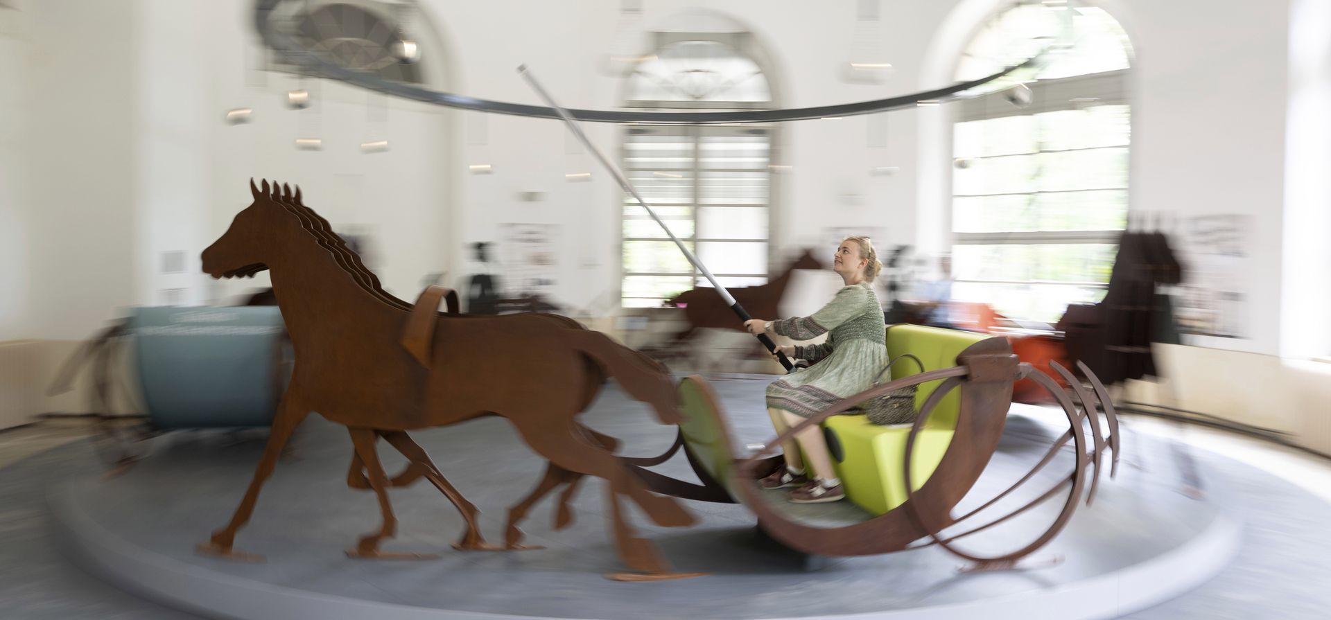 Sophie Weiss sentada en una interpretación moderna del carrusel Ringrenn durante una visita al invernadero del Palacio Pillnitz, en Dresde, Alemania, el jueves 24 de agosto de 2023. El carrusel es parte de la exposición "Los juegos del rey", cuyo objetivo es dar vida a la alegría veraniega de la corte. (Sebastián Kahnert/dpa vía AP) Sophie Weiss sentada en una interpretación moderna del carrusel Ringrenn durante una visita al invernadero del Palacio Pillnitz, en Dresde, Alemania, el jueves 24 de agosto de 2023. El carrusel es parte de la exposición "Los juegos del rey", cuyo objetivo es dar vida a la alegría veraniega de la corte. (Sebastián Kahnert/dpa vía AP)