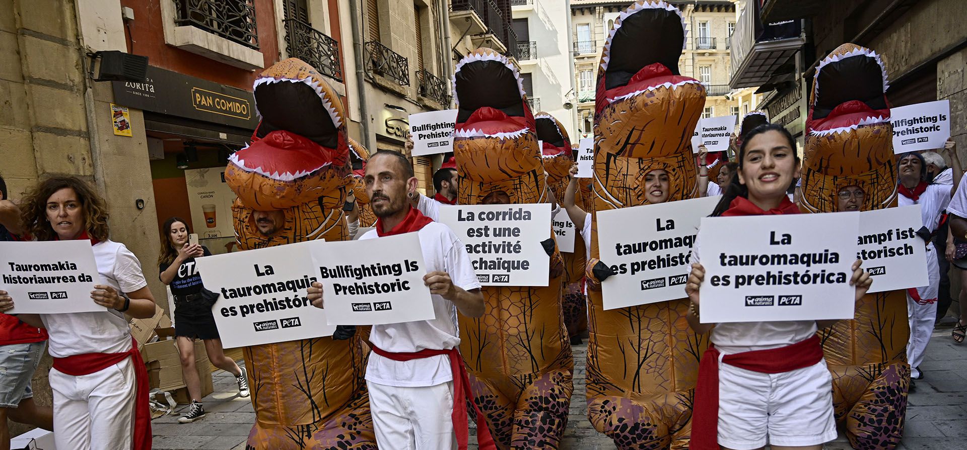 Personas vestidas como dinosaurios y con los colores blanco y rojo de San Fermín protestan contra la crueldad hacia los animales antes del inicio del festival de San Fermín, que ha sido cancelado durante los últimos dos años debido a las restricciones del coronavirus, en Pamplona, norte de España, el martes 5 de julio. 2022. Personas de todo el mundo acuden a Pamplona para participar en los nueve días del festival que comienza el miércoles 6 de julio.