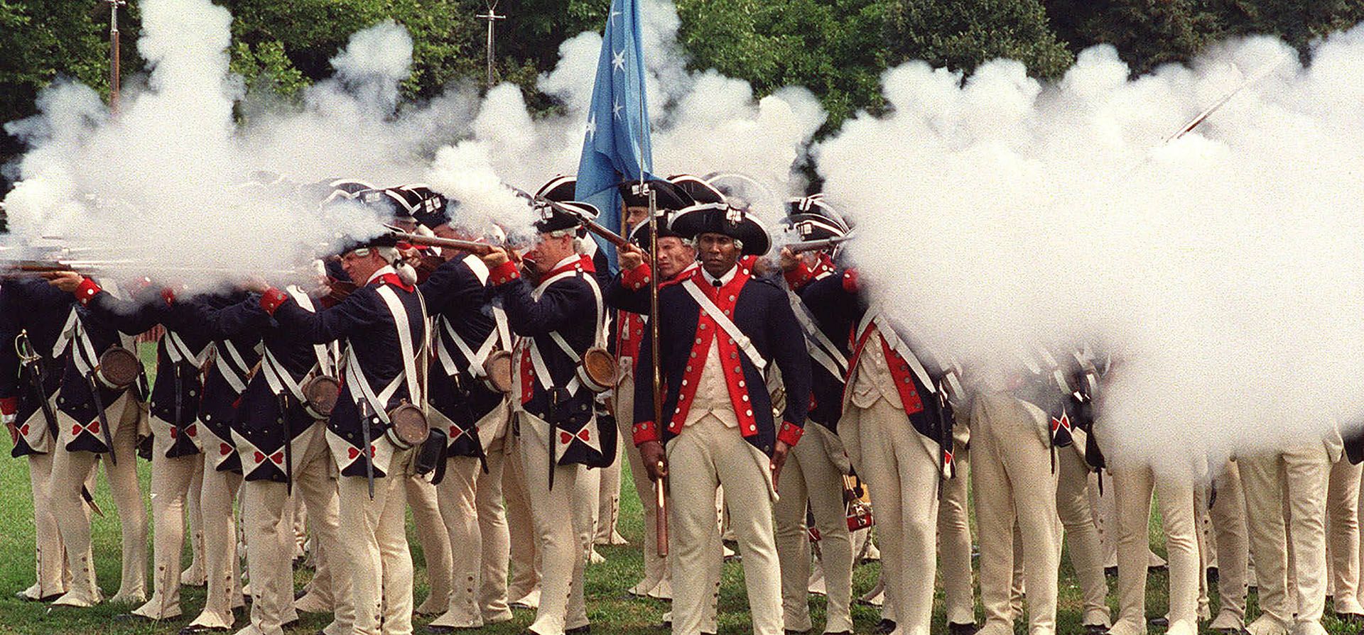 Miembros de las fuerzas estadounidenses durante la Guerra Revolucionaria disparan sus rifles durante una recreación que celebra el 225 aniversario de la Batalla de Brooklyn, el 18 de agosto de 2001. Algunos recreadores de batallas históricas en Nueva York están preocupados sobre la nueva ley de armas del estado que declara parques, propiedades gubernamentales y una larga lista de otros lugares prohibidos para las armas a partir de septiembre de 2022.