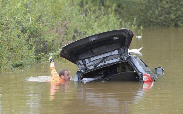 Personal de rescate revisa un automóvil sumergido en una carretera inundada en Falun, Suecia. Las fuertes lluvias en el este del país han anegado algunas áreas, con varias carreteras y viaductos desbordados por las lluvias.